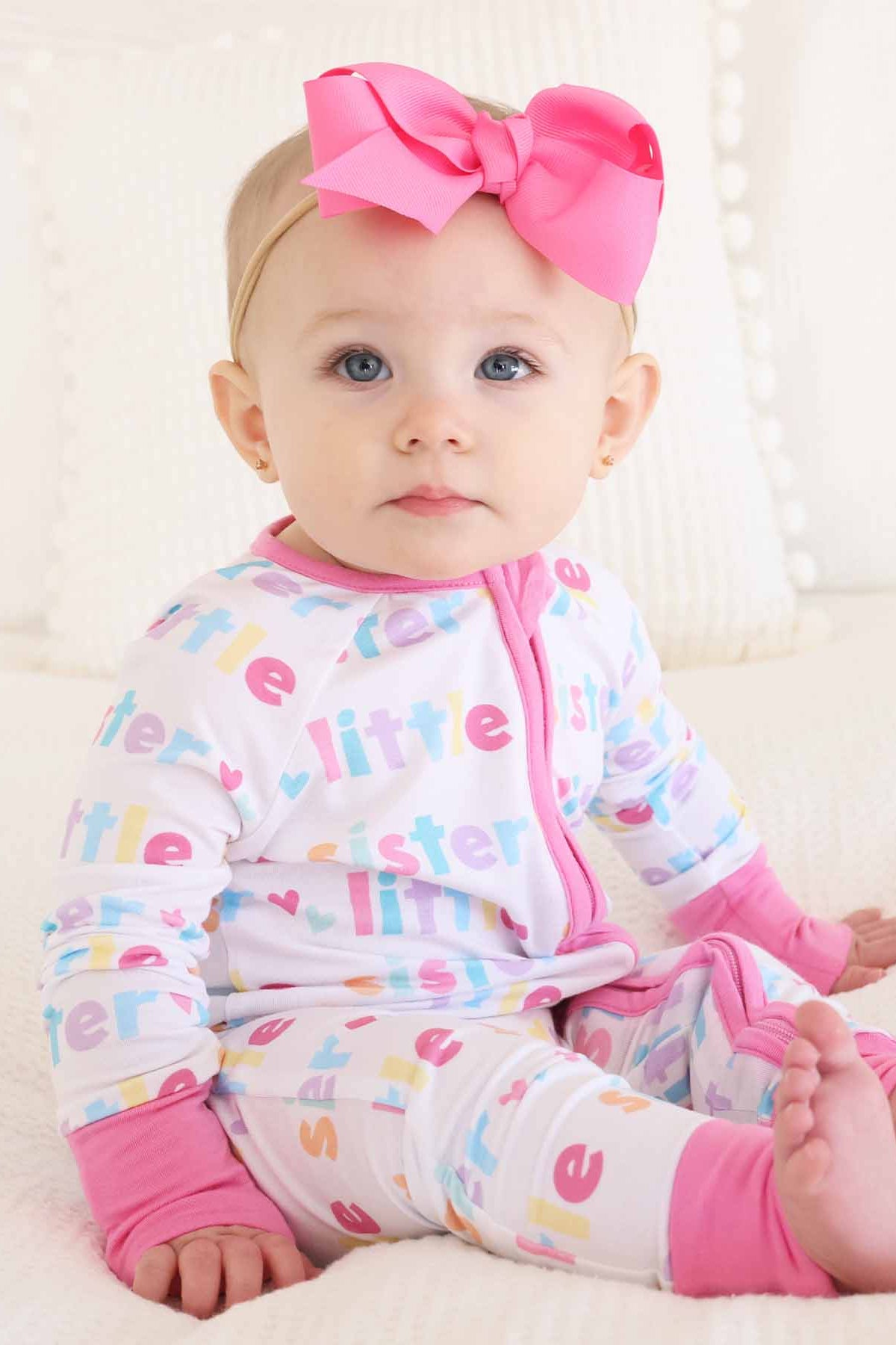 baby girl wearing little sister zip romper with bubblegum pink bow headband