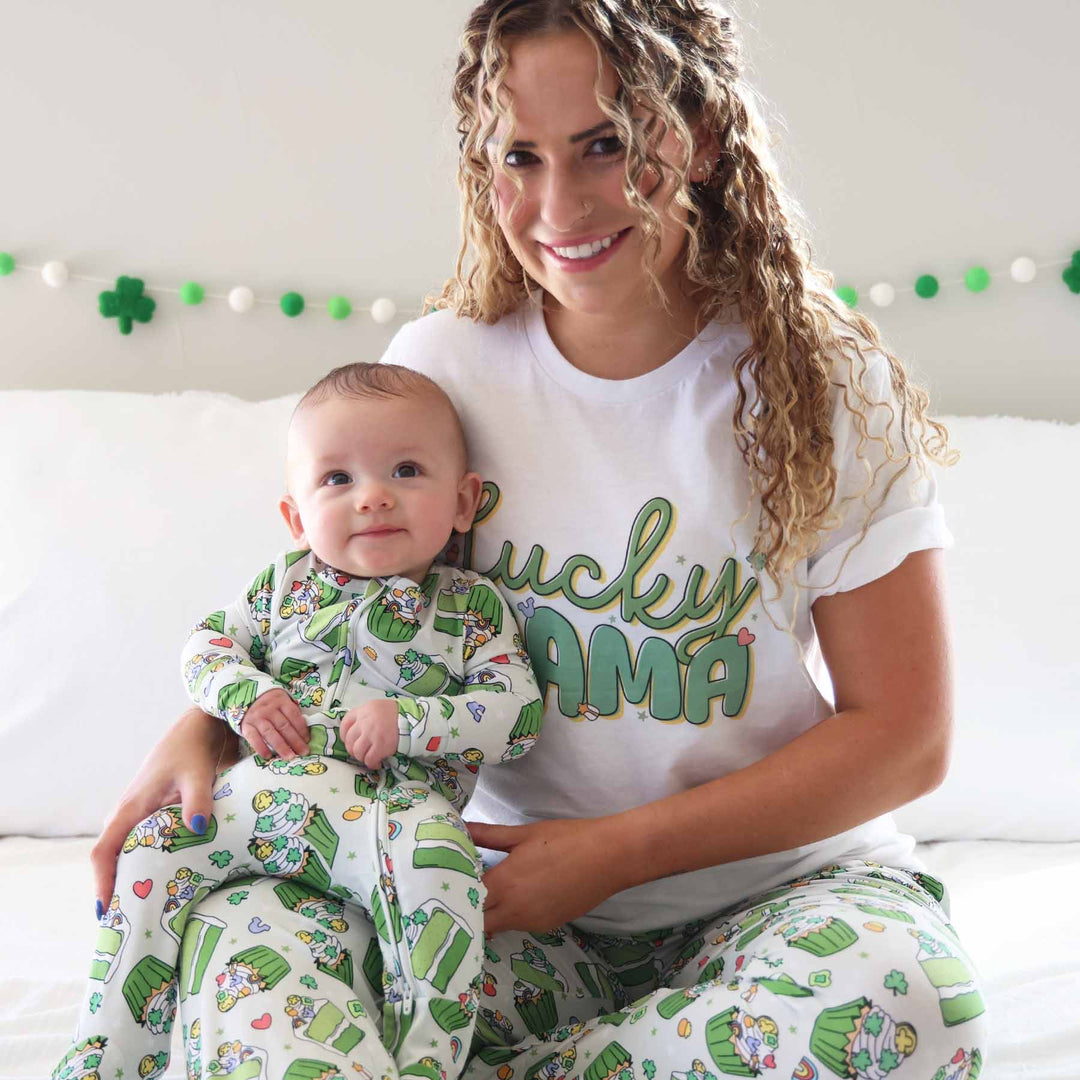 baby boy in st. patrick's day footie sitting on mom's lap who is wearing matching pajama pants and a "lucky mama" t-shirt