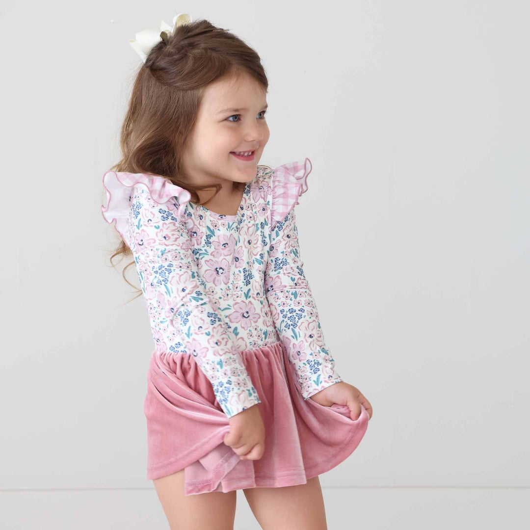 girl wearing a long sleeve floral leotard holding the velvet skirt 