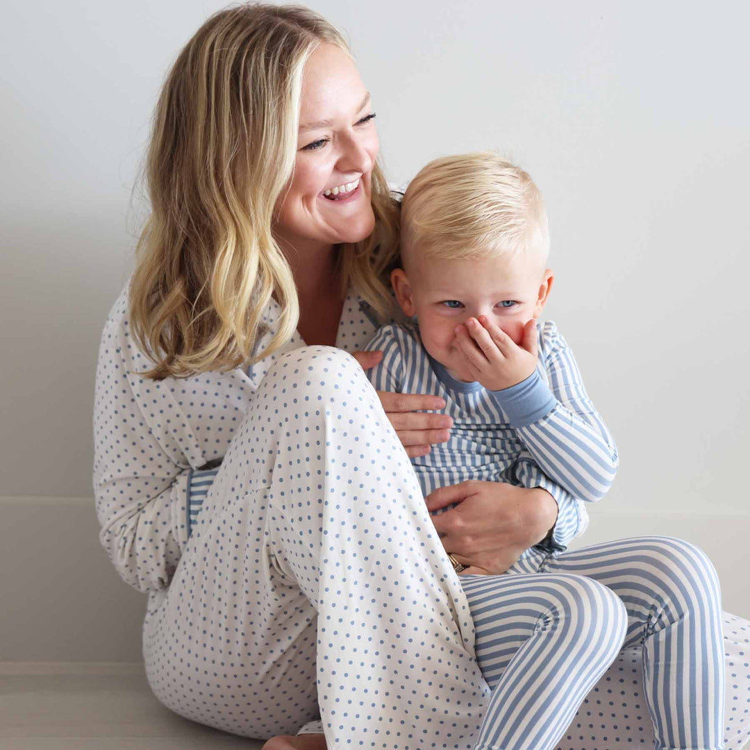 woman wearing a long sleeve lounge set white with blue polka dots with son on her lap in coordinating pajama set with blue and white stripes 