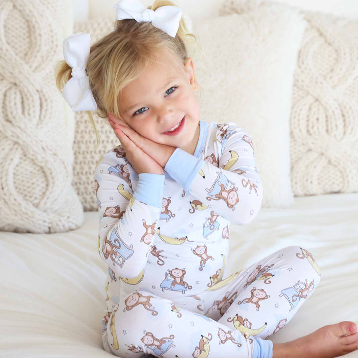 girl with her hands together like she's sleeping wearing sleeping monkey pajamas 
