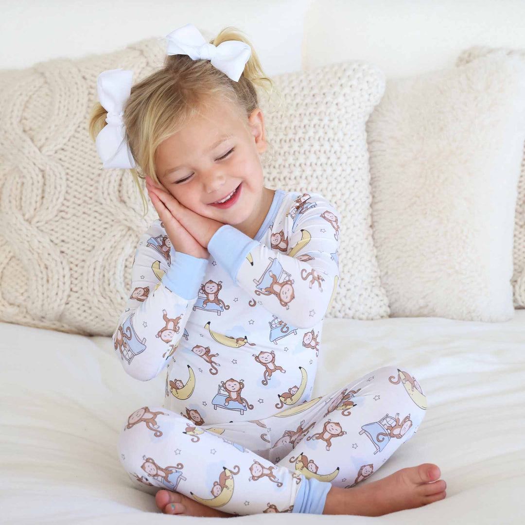 girl wearing pajamas with monkeys jumping on a bed and sleeping on banana moons