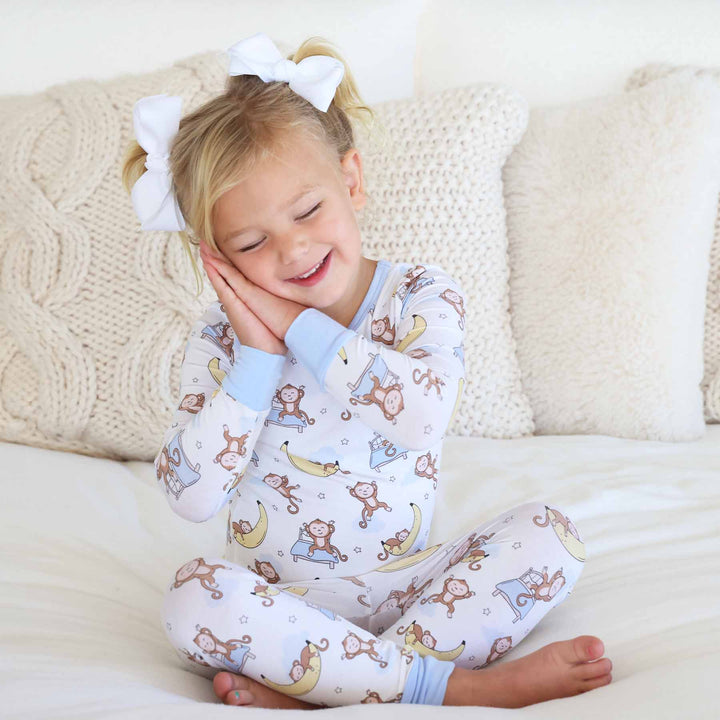 girl wearing pajamas with monkeys jumping on a bed and sleeping on banana moons