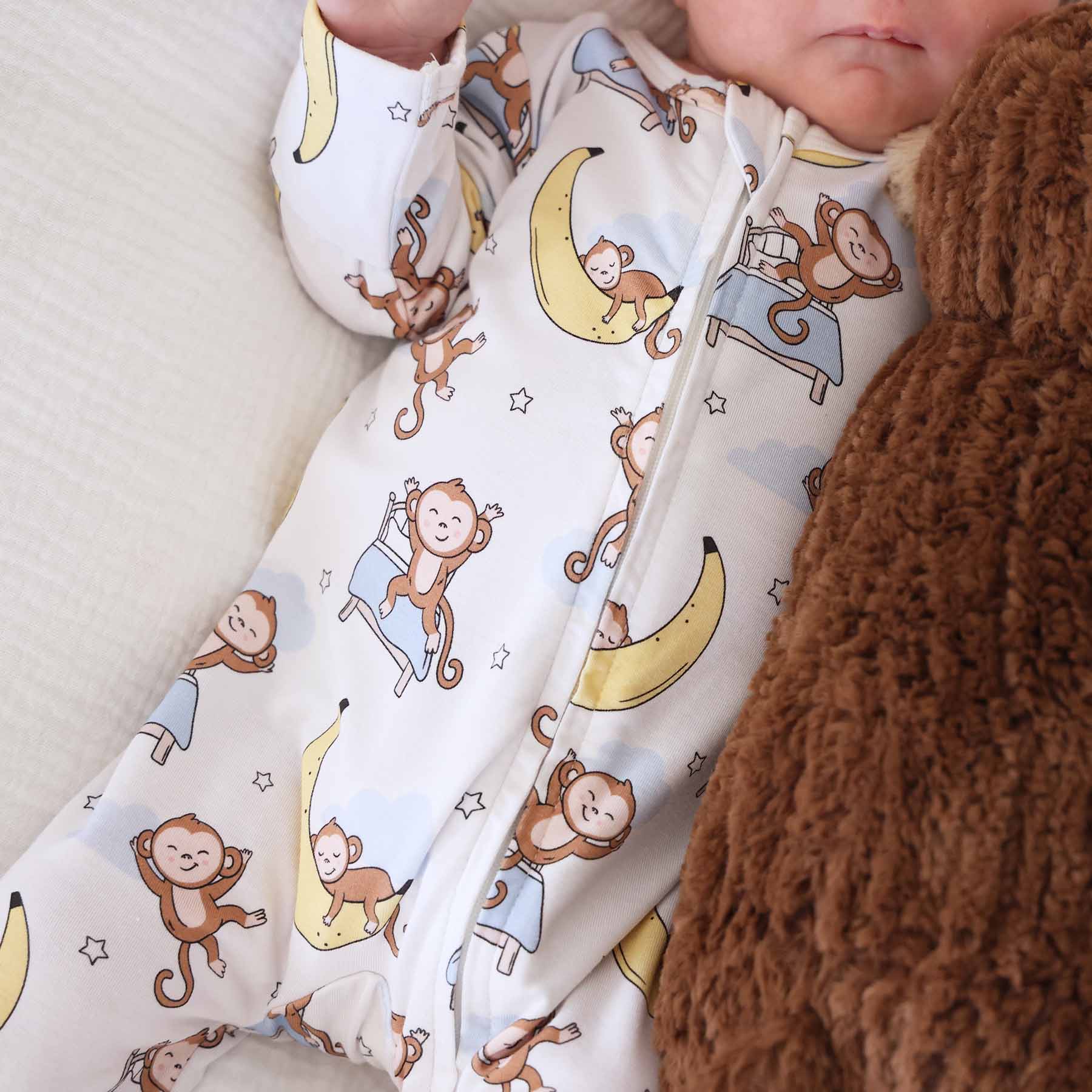 sleeping money on bed and banana moon with stars in the background bamboo zipper footie for babies 