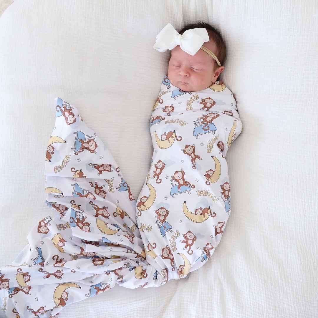 sleeping baby wrapped in a monkey and banana personalized swaddle blanket 