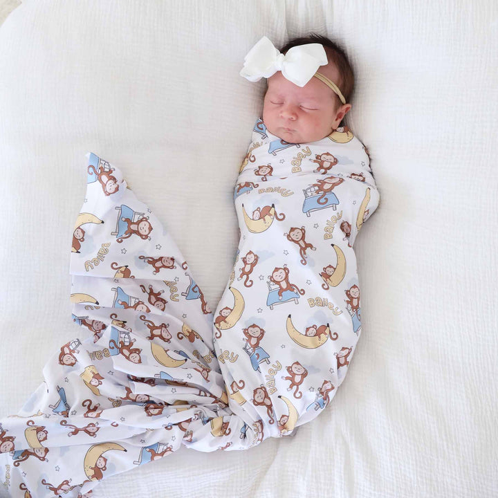sleeping baby wrapped in a monkey and banana personalized swaddle blanket 