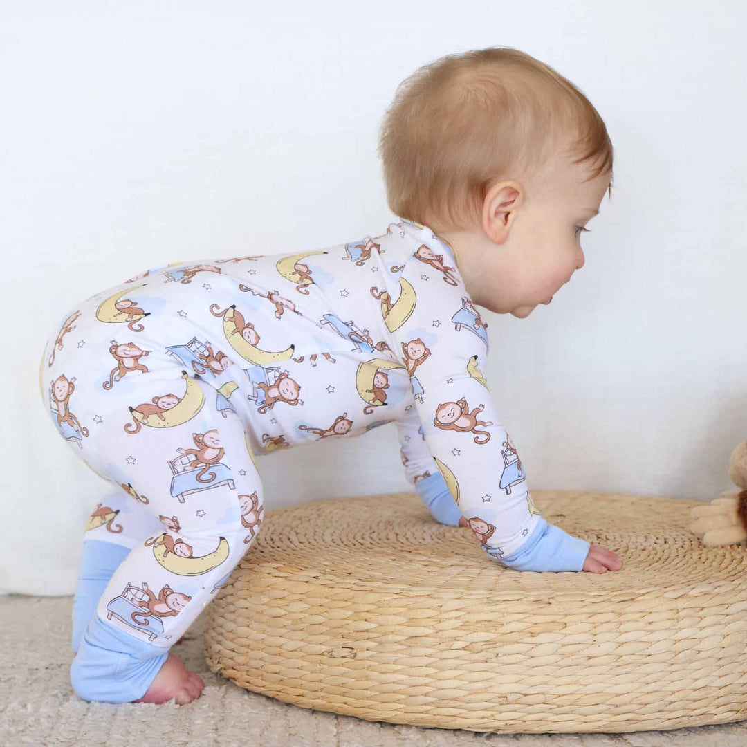toddler crawling on wooden platform in monkey pajama romper 
