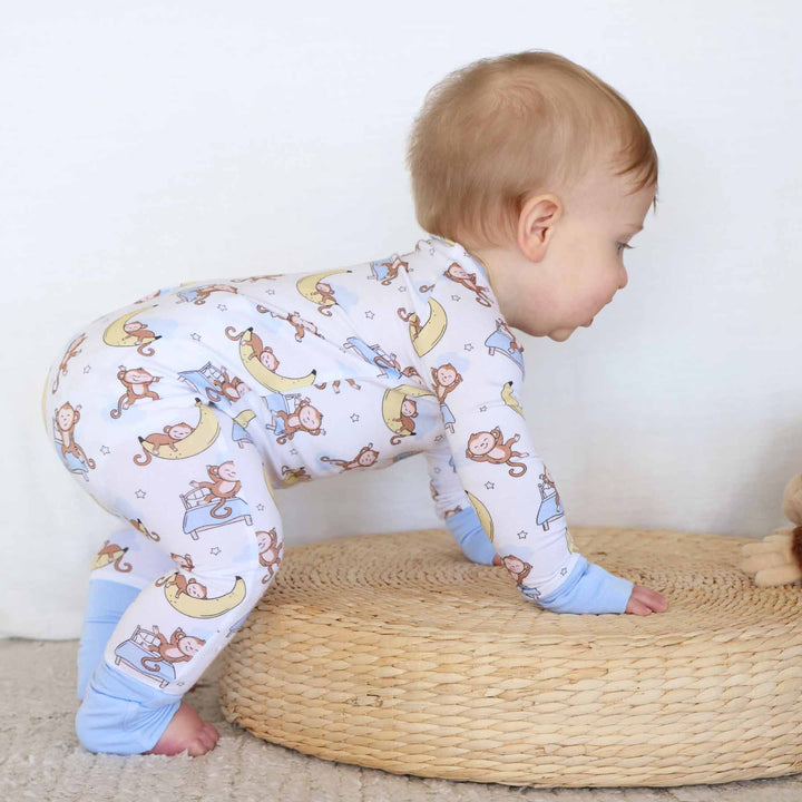 toddler crawling on wooden platform in monkey pajama romper 