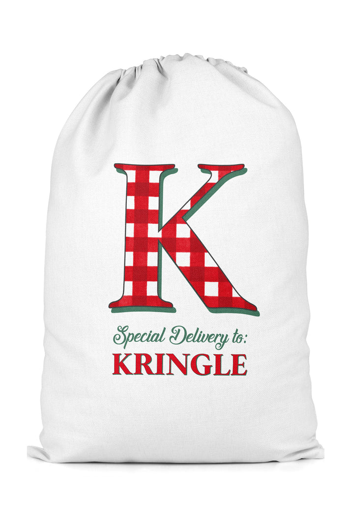 A white Caden Lane Christmas Santa sack featuring a large red and white gingham checkered letter 'K' with green outlines, and the text 'Special Delivery to: KRINGLE' printed below.
