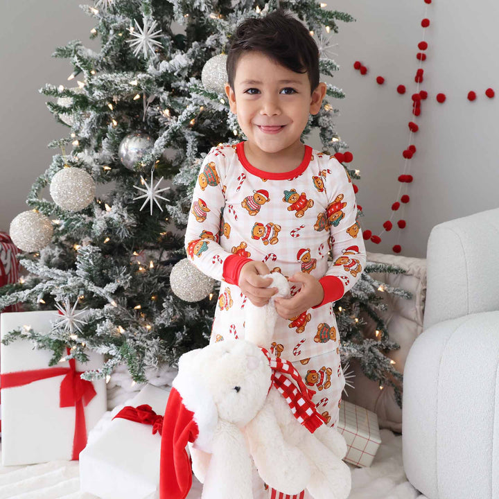 bow in bear christmas pajamas holding a christmas bunny stuffed animal