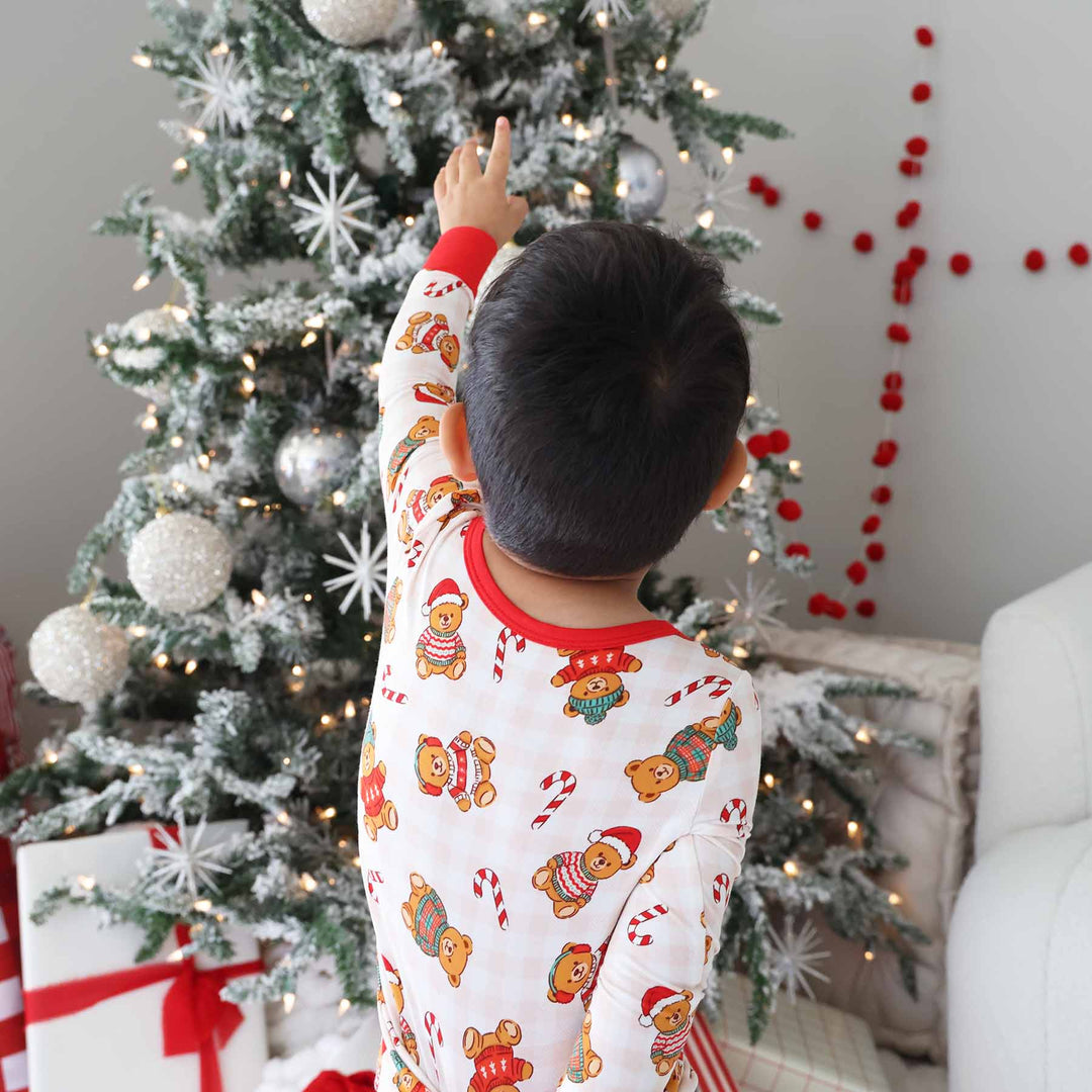 boy wearing neutral gingham two piece pajama set with teddy bears wearing christmas sweaters and candy canes 