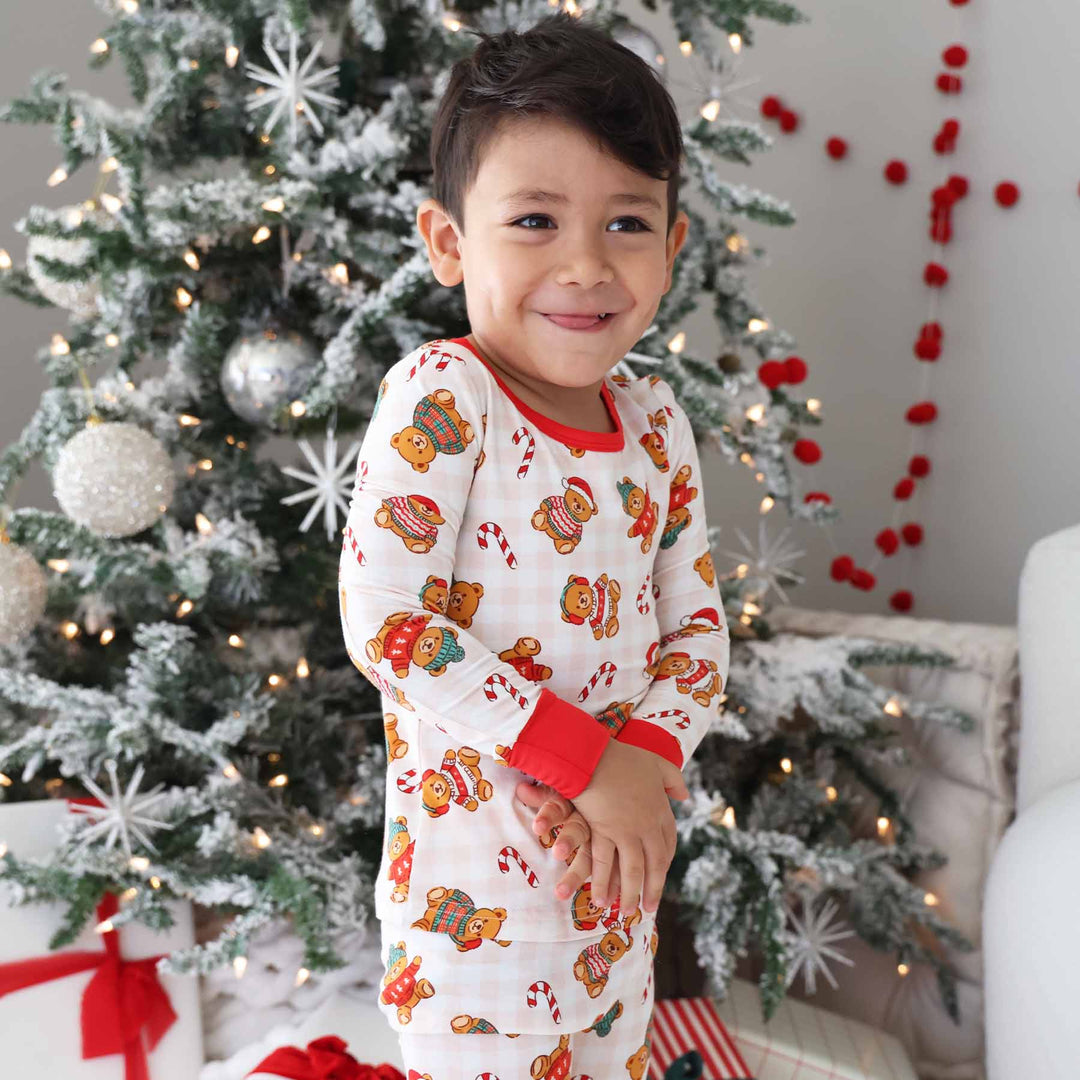 boy wearing neutral gingham christmas pajamas with teddy bears wearing sweaters 