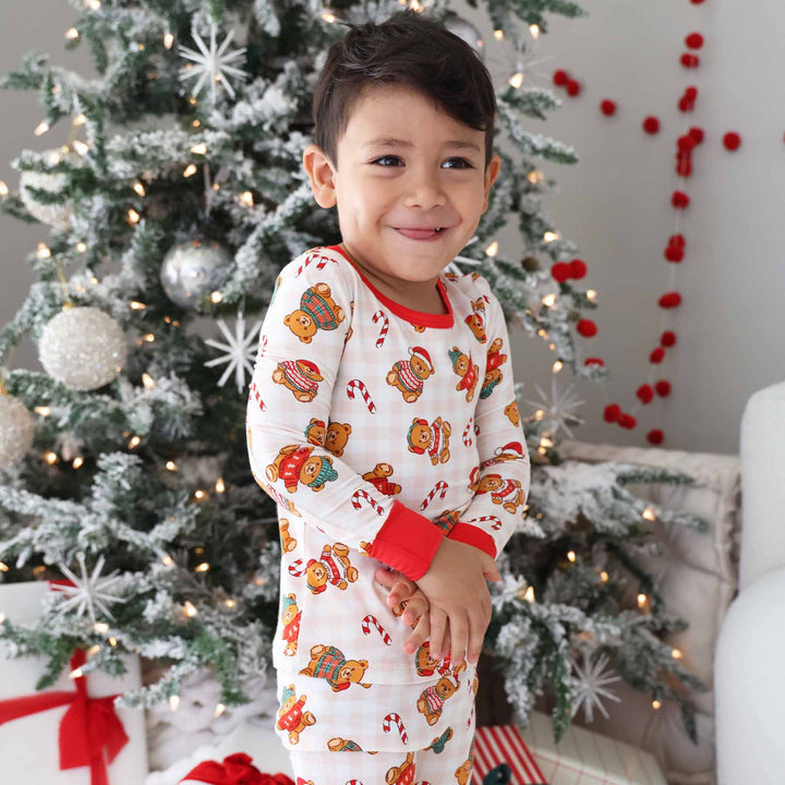 boy wearing neutral gingham christmas pajamas with teddy bears wearing sweaters 