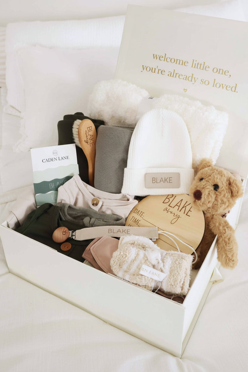 deluxe baby shower gift box bundle with neutral 2pc waffle, zipper footie, knot gown, wood  stats, swaddles, bottle labels, burps, socks, paci clip, beanie, lovey, blanket, hooded towel, hair brush, bear stuffed animal
