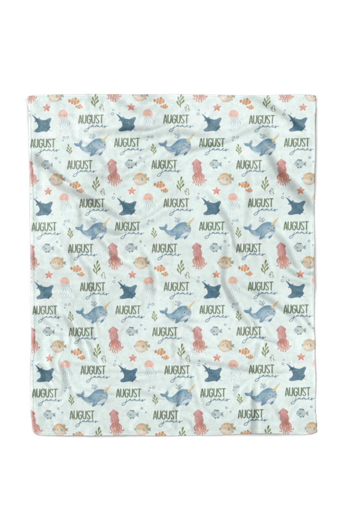 Flat lay of a fully unfolded personalized Caden Lane Ocean Dreams blanket in seafoam, showing the full repeating pattern of sea creatures and custom name