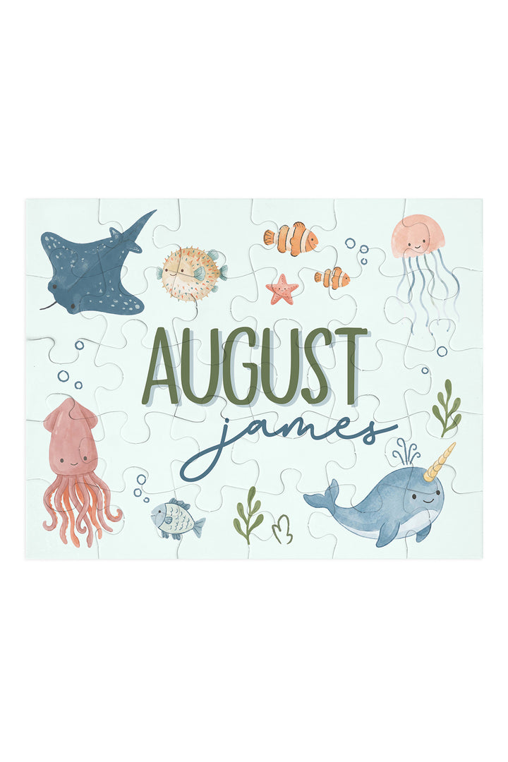 Flat lay of an assembled personalized Caden Lane Ocean Dreams jigsaw puzzle in seafoam, showing sea creatures and custom name
