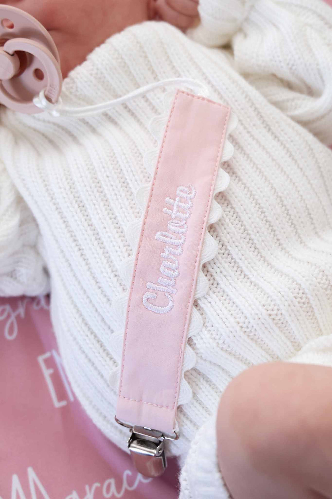 light pink pacifier clip embroidered with name in white thread with white scalloped edges