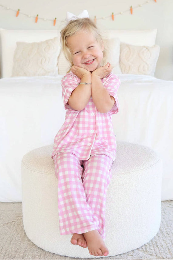 girl sitting on ottoman wearing a pink gingham lounge set for easter 