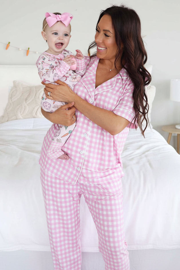 mom wearing pink gingham short sleeve lounge set holding a baby girl in matching easter zip romper pajama 