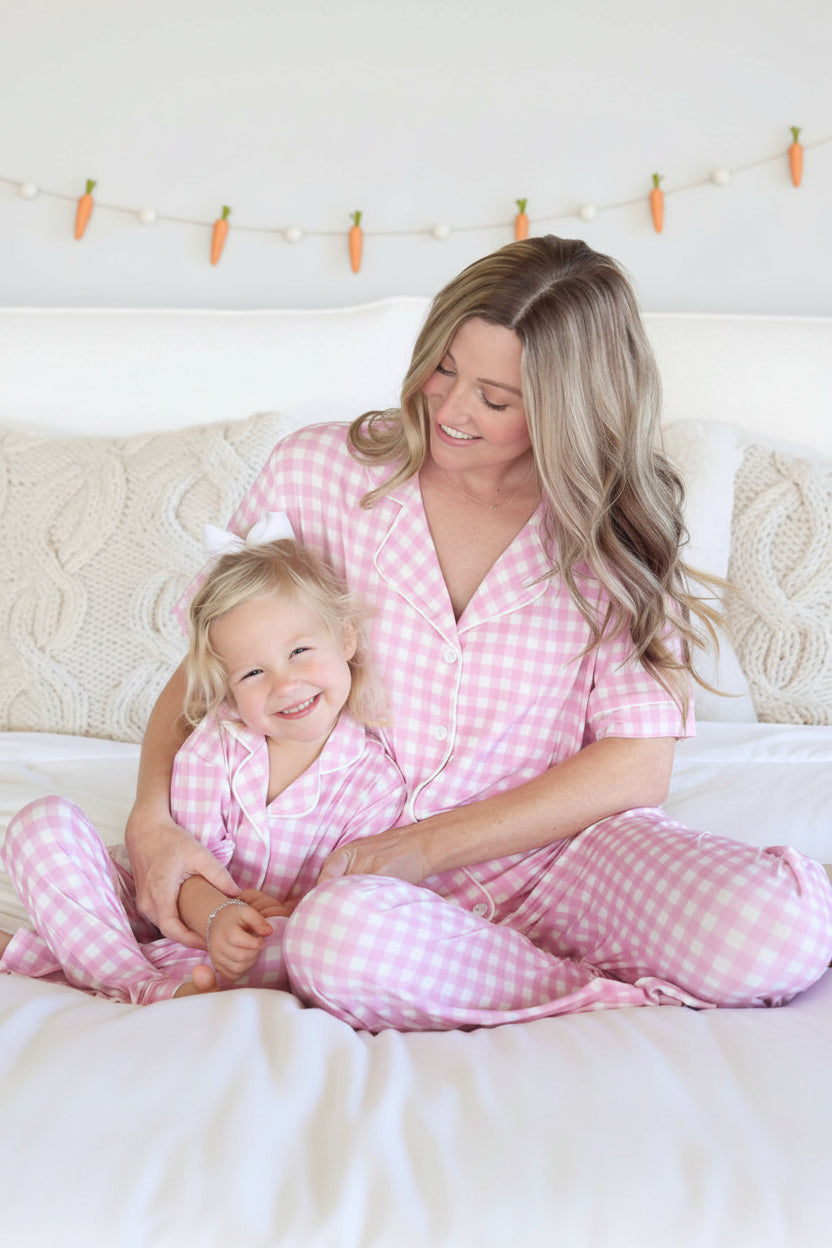 mom and daughter sitting on bed in pink and white gingham lounge sets for easter 