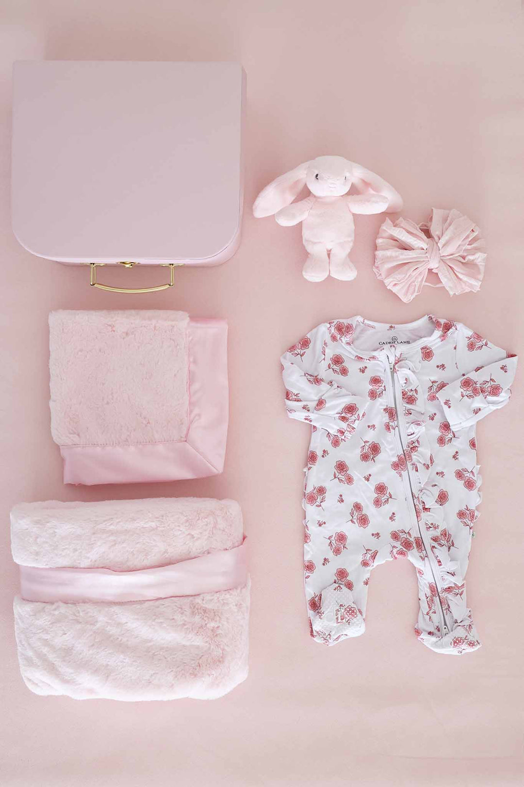 contents of newborn keepsake box with blanket, lovey, stuffed bunny, bow and floral footie