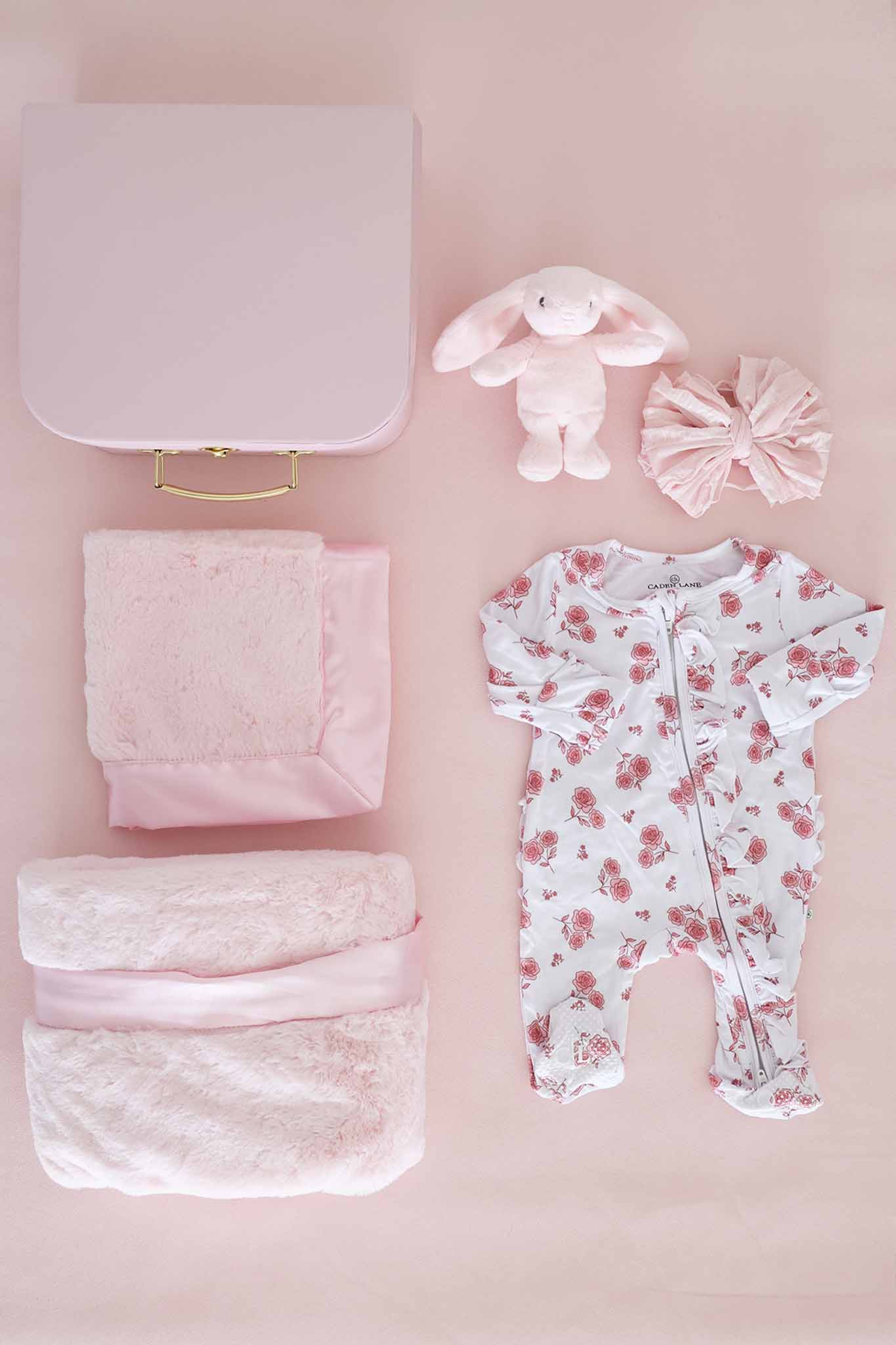 contents of newborn keepsake box with blanket, lovey, stuffed bunny, bow and floral footie