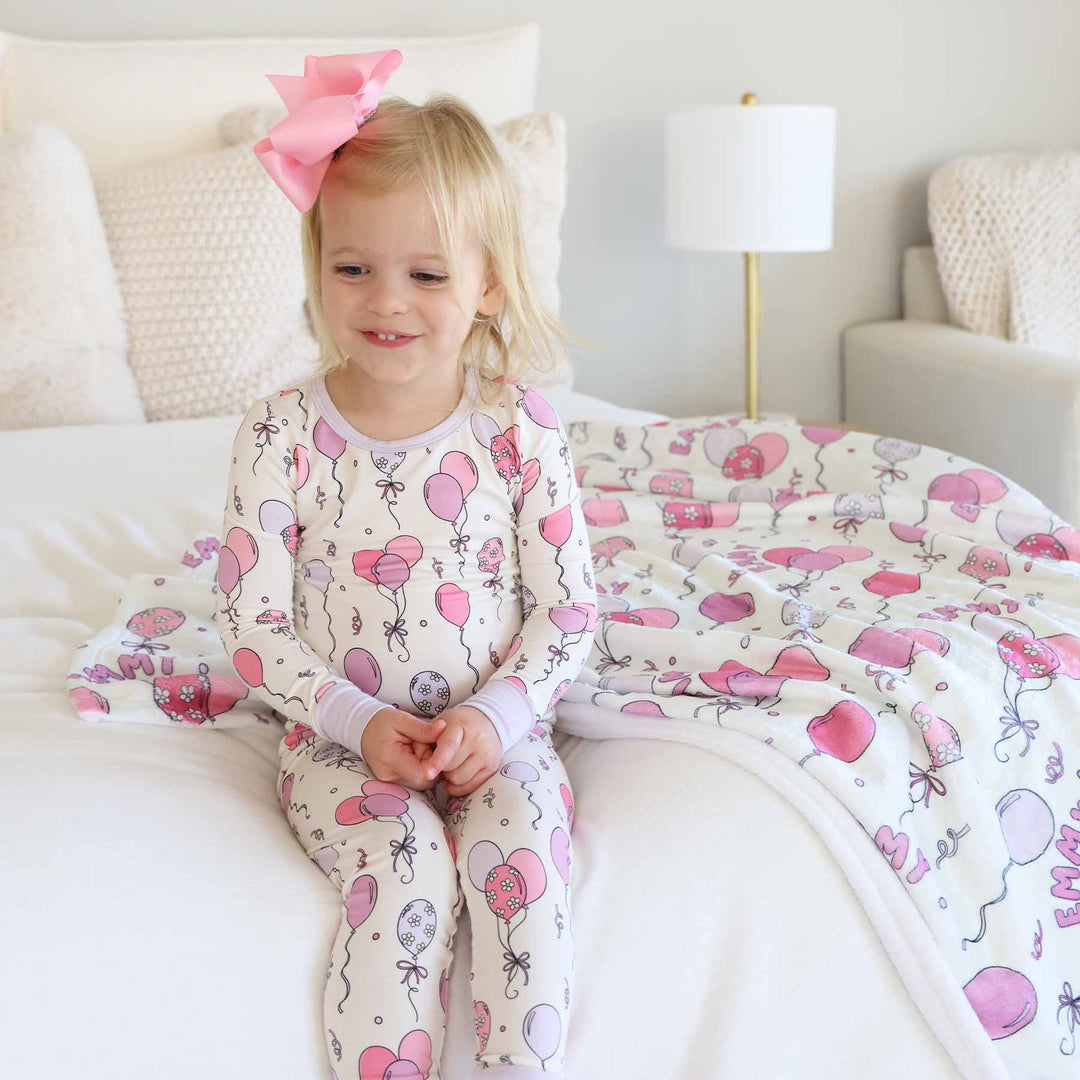 girl wearing party themed two piece pajama set with pink and purple balloons 