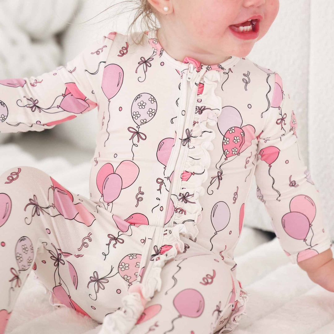 ruffle zipper footie for girls with pink and purple balloons and streamers for birthdays