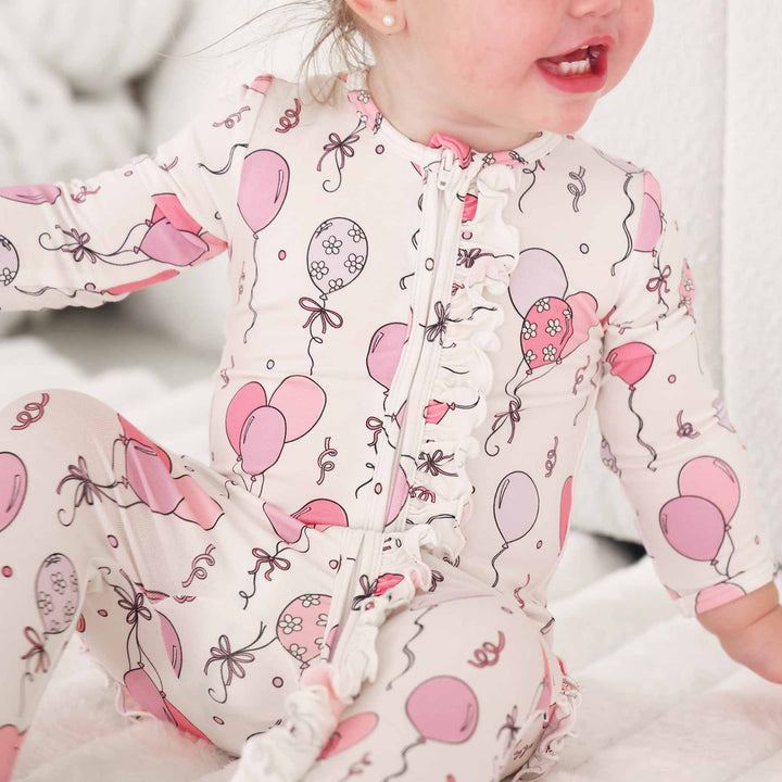 ruffle zipper footie for girls with pink and purple balloons and streamers for birthdays