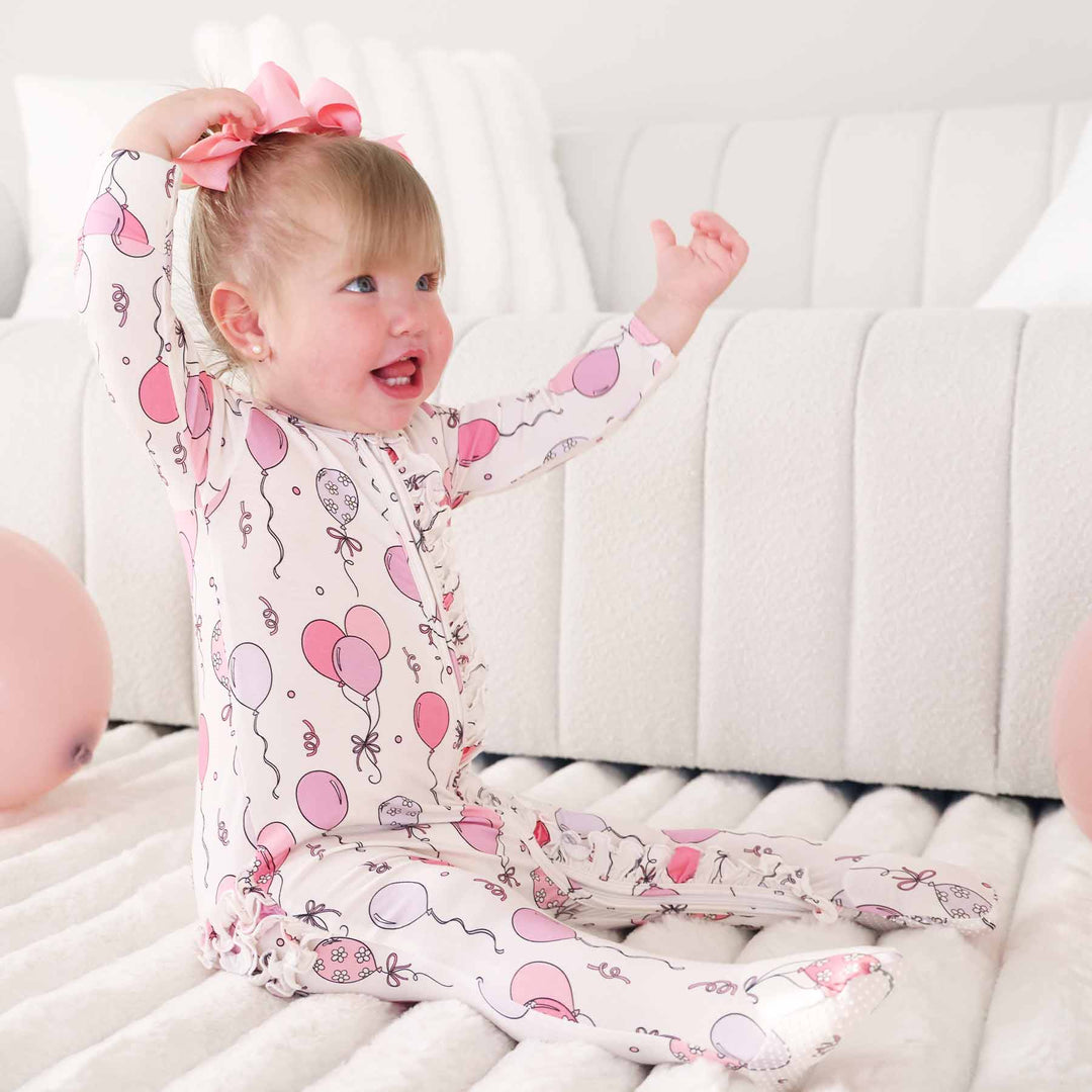 baby girl wearing a pink and purple balloon and streamer footie pajama 
