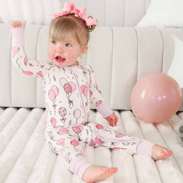 girl wearing a pink party convertible zip romper pajama for babies and toddlers 