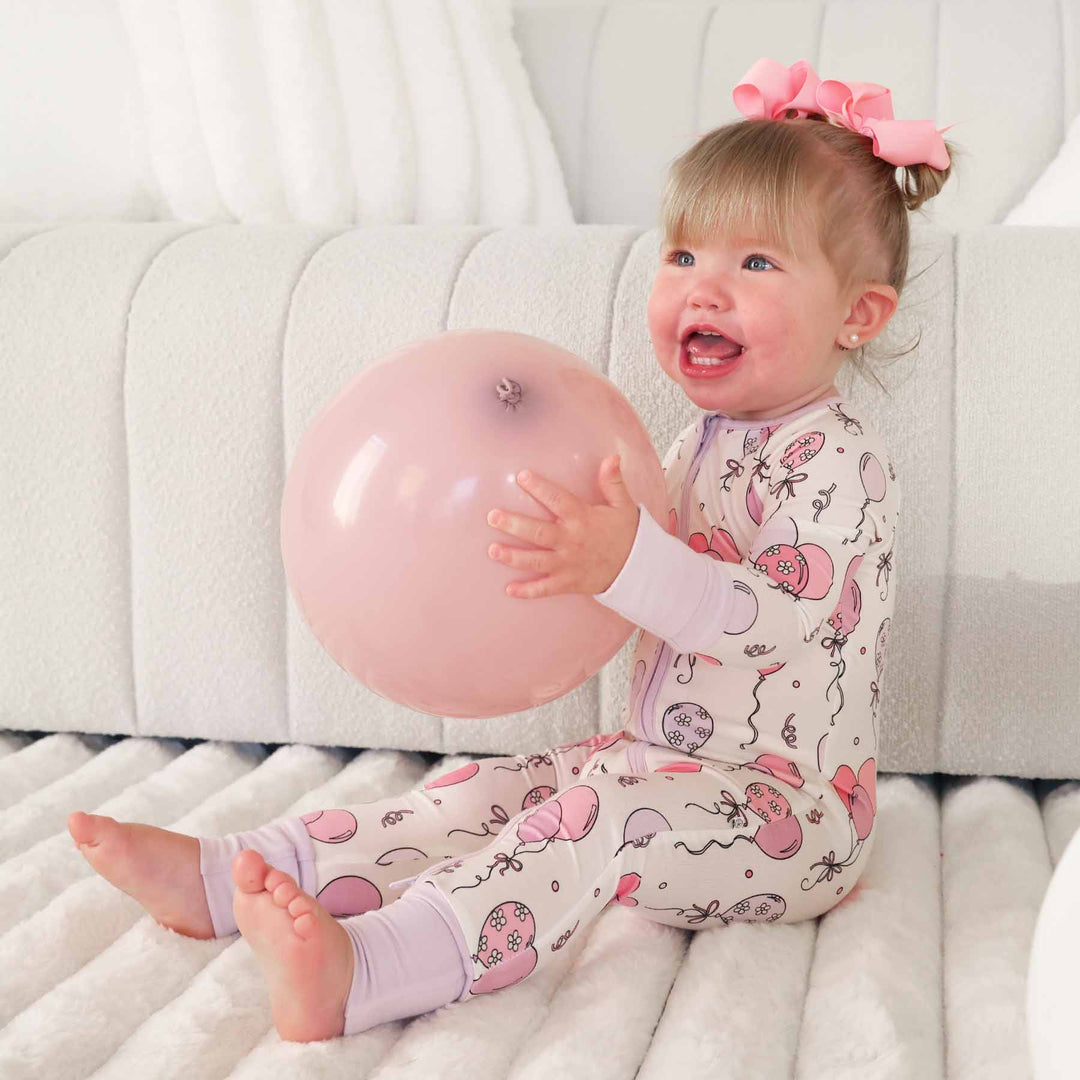 girl wearing a balloon convertible zip romper pajama holding a balloon 