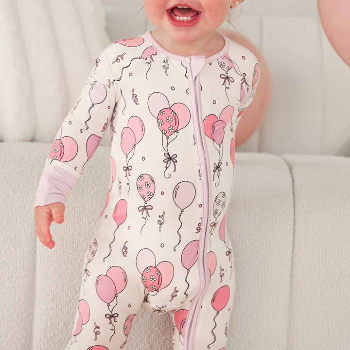 zip romper pajama with pink and purple balloons with daisies and streamers 