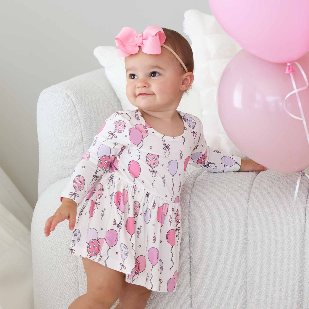 girl wearing pink balloon bodysuit dress with a pink ribbon bow headband 