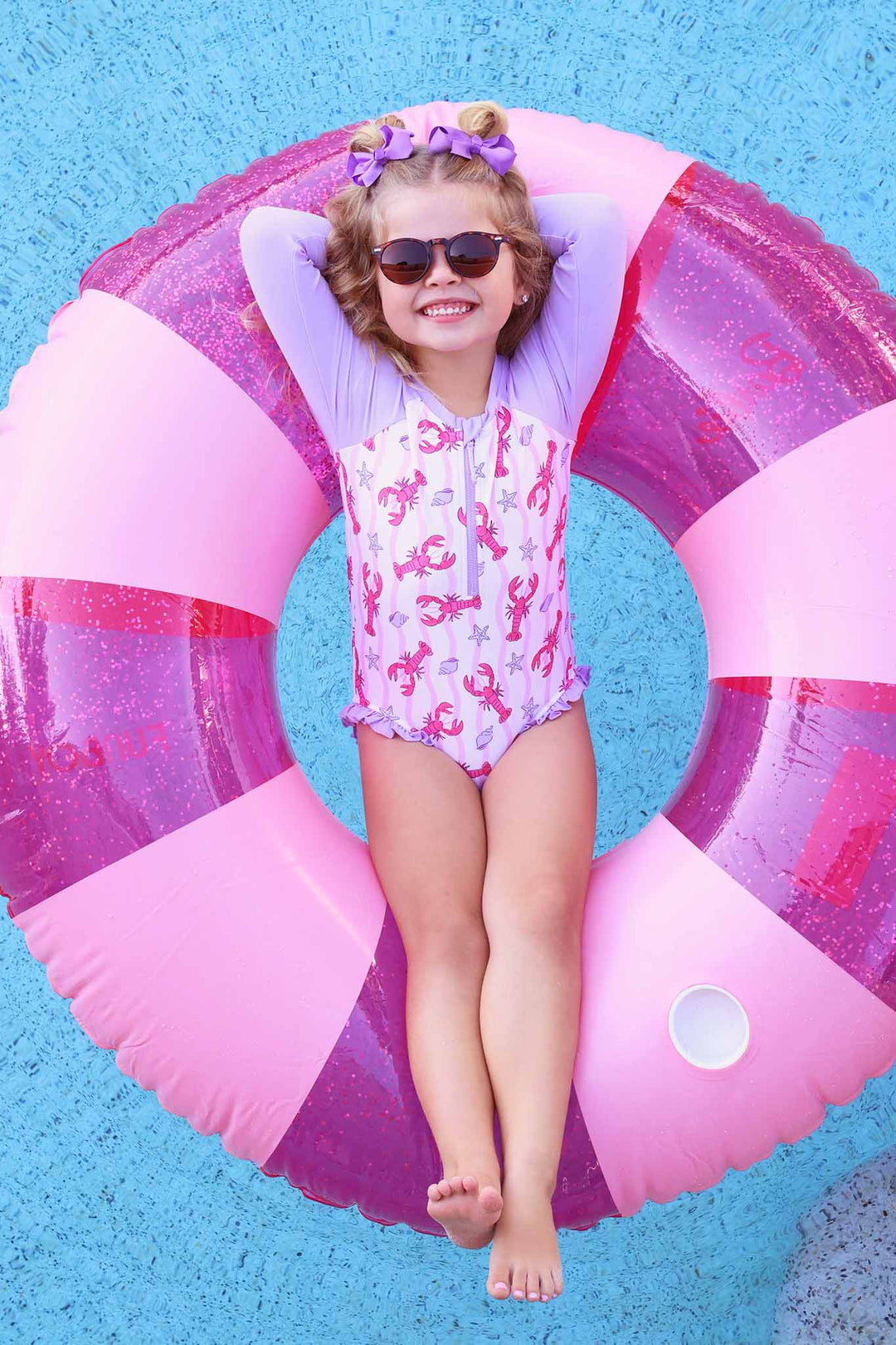 girl floating on innertube in the pool in lobster long sleeve rash guard swimsuit 