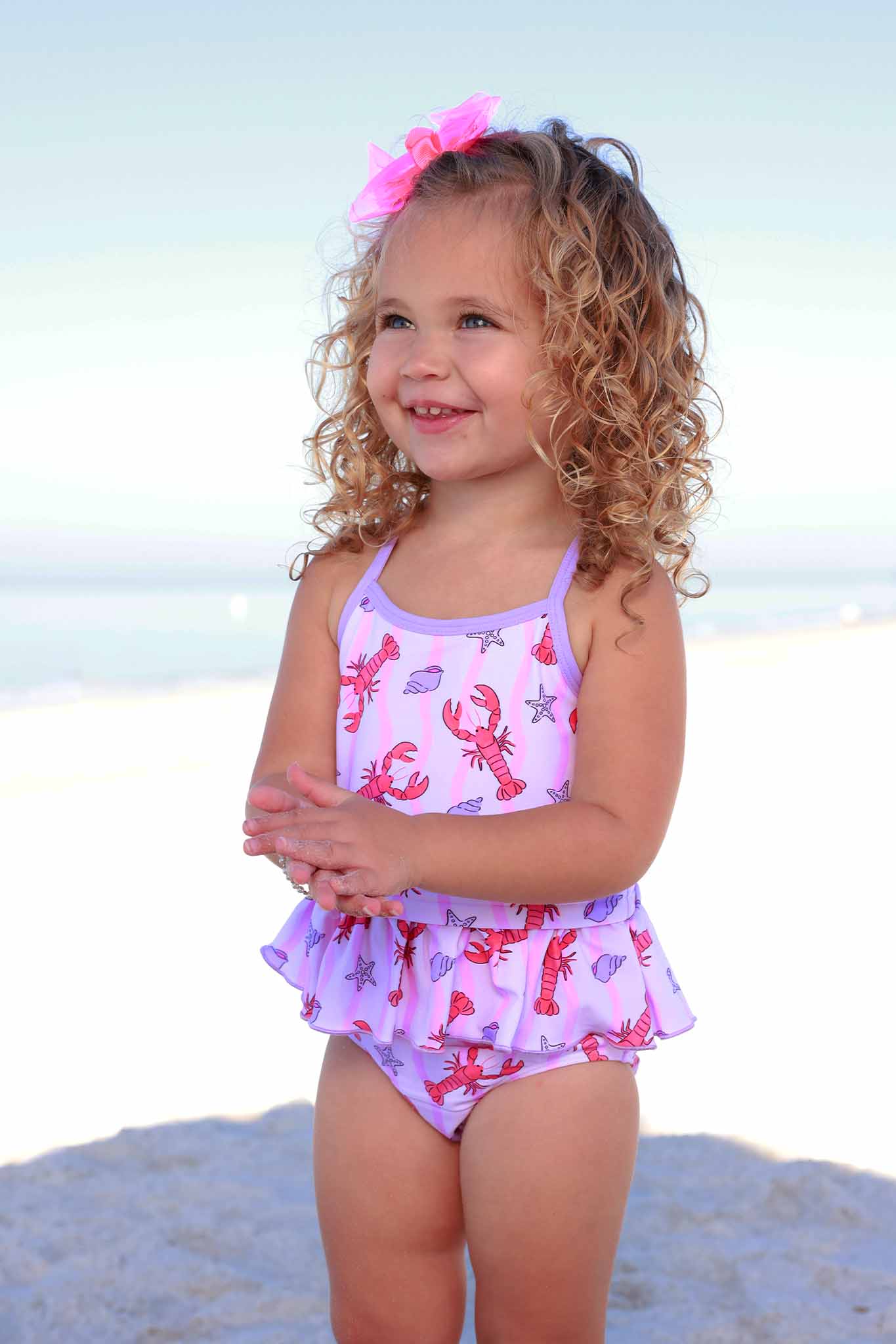 girl standing on beach in purple lobster, seashell and starfish upf 50+ strappy tankini 