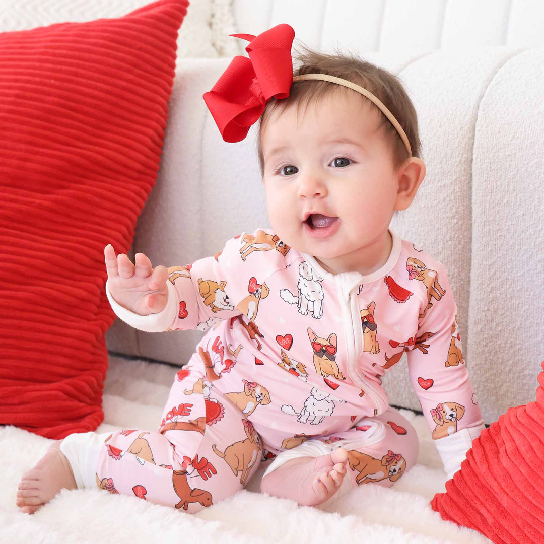 baby girl wearing a pink puppy and heart convertible zip romper pajama 