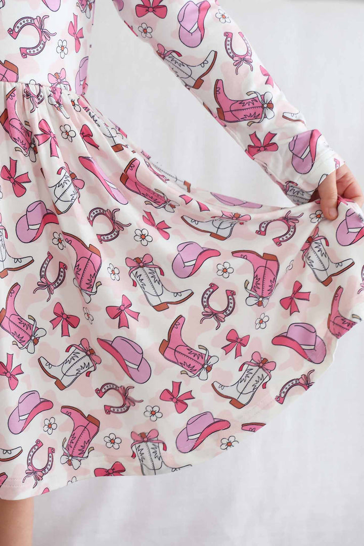 closeup of pink rodeo dreams dress with cowgirl boots, hats, horseshoes, bows and daisies 
