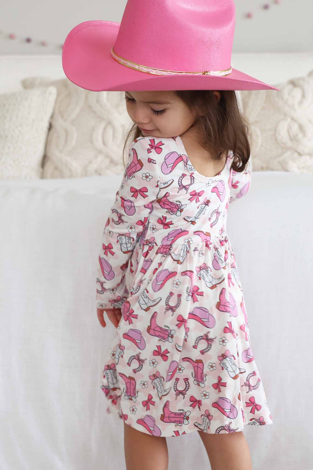 girl wearing pink rodeo dreams long sleeve dress and pink cowgirl hat 