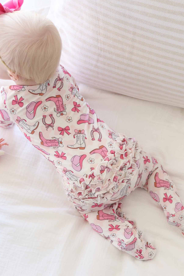 cowgirl themed zipper footie for baby girls in pink with ruffles on the bottom