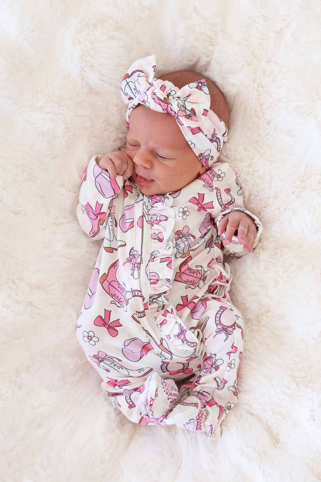 newborn girl in pink rodeo ruffle zipper footie with matching headwrap
