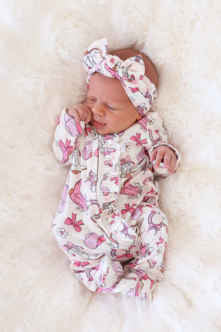 newborn girl in pink rodeo ruffle zipper footie with matching headwrap
