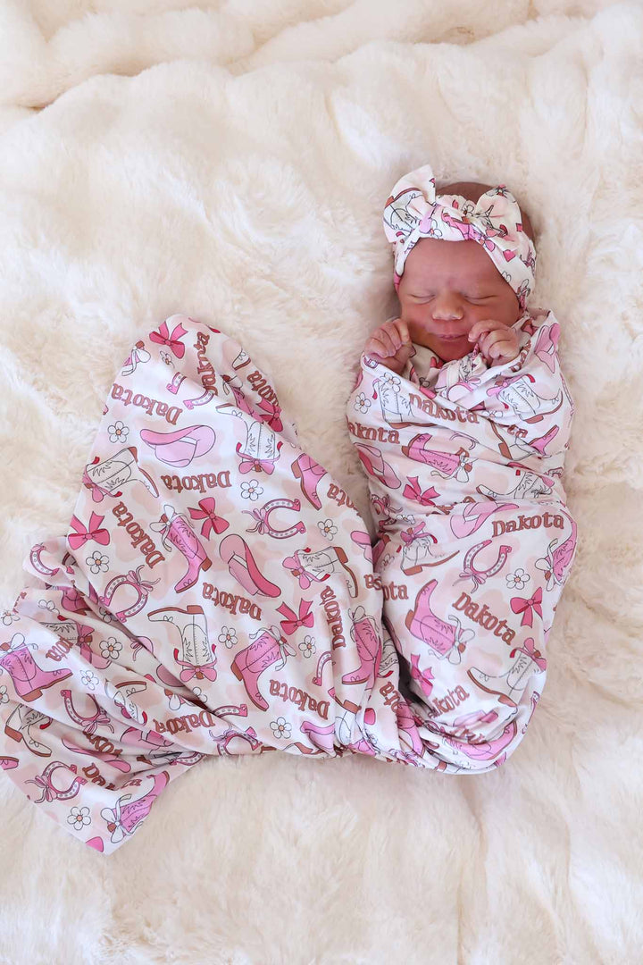 newborn girl wrapped in pink rodeo dreams personalized swaddle blanket with a matching headwrap