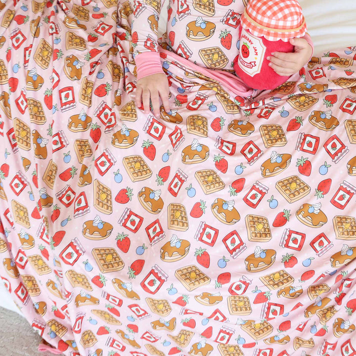 girl with ink breakfast themed bamboo blanket wearing matching pajama set 