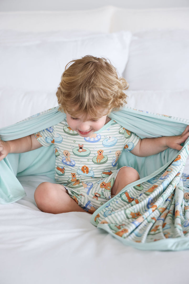 boy in poolside pups two piece pajama set with matching bamboo blanket over his shoulders