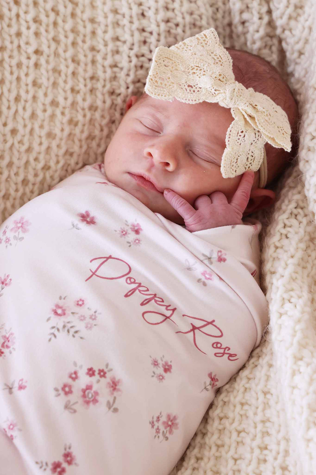 baby girl with lace ribbon bow headband on her head wrapped in the precious posies personalized swaddle blanket 