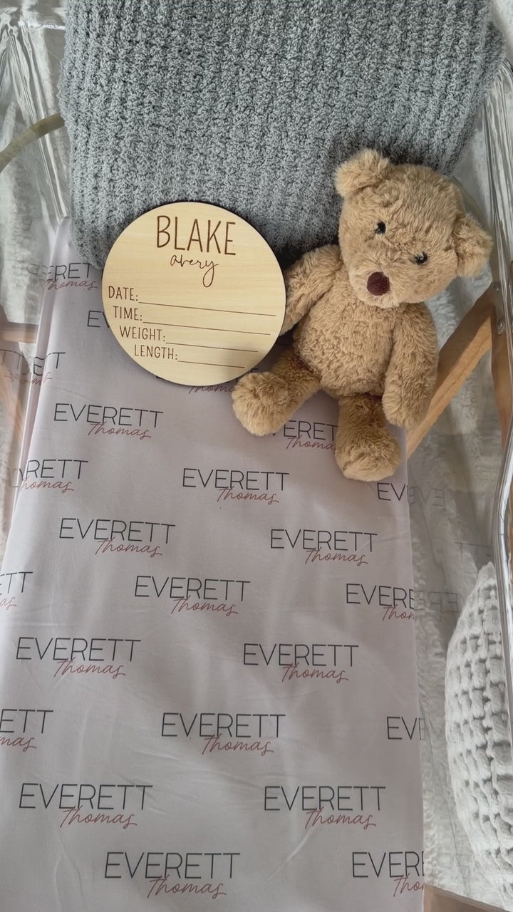 white personalized swaddle blanket with green and orange letters