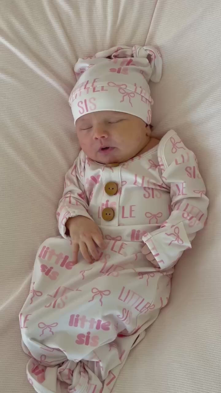 baby girl laying on pastel pink swaddle blanket in little sis newborn knot gown and hat set 