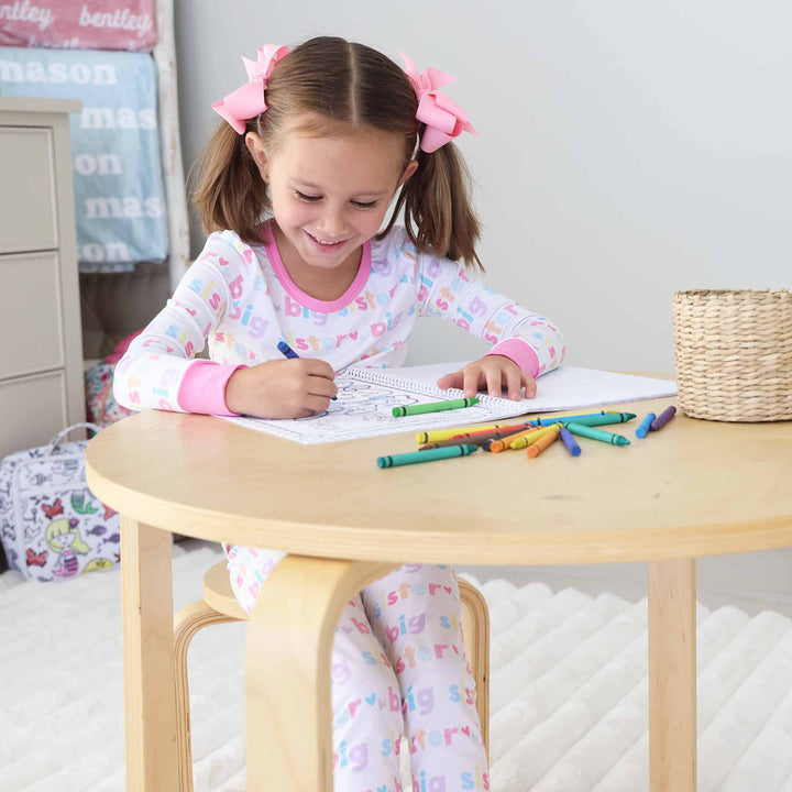 little girl sitting at table coloring a princess coloring book 