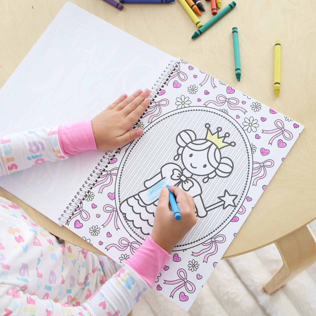 little girl coloring a princess coloring book 